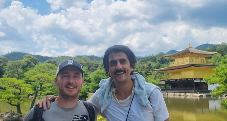 Twee vrienden poseren voor een traditionele Japanse structuur aan het water.