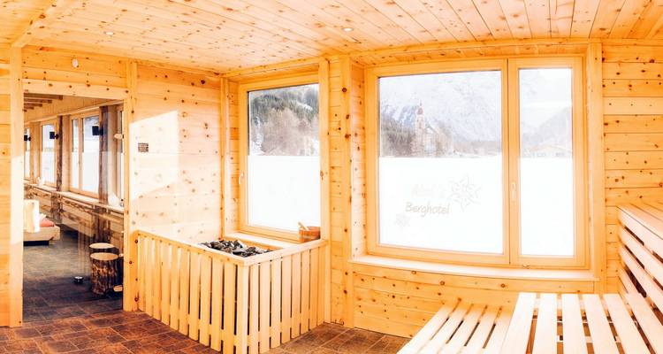 Interior of a wooden sauna with snowy landscape view through windows.
