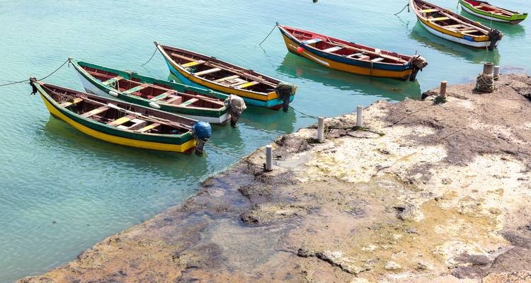 Small boats moored near a rocky shore in turquoise waters.