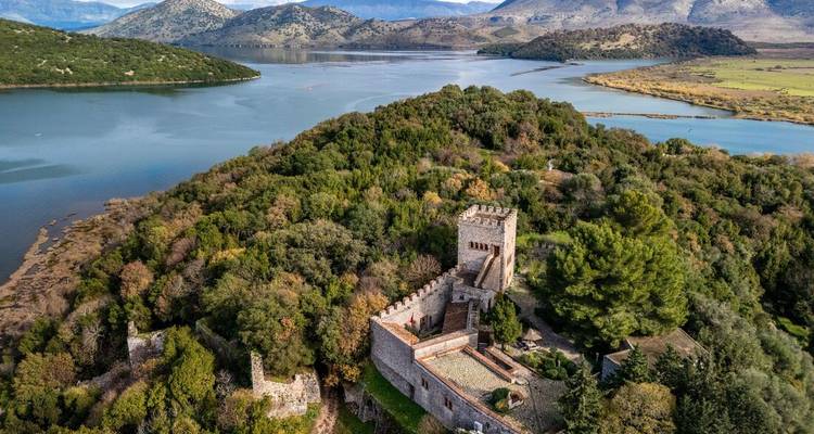 Vue aérienne d'un château sur une île boisée entourée d'eau.