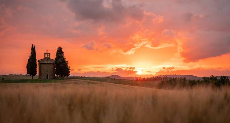 Chapel and cypress trees under a sunset sky.