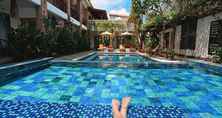 Personne se détendant au bord d'une piscine d'un bleu éclatant avec des chaises longues en arrière-plan.