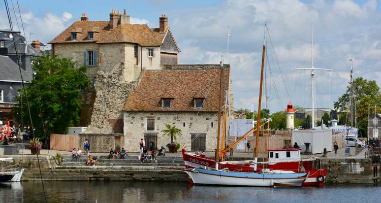 Port historique avec de vieux bâtiments en pierre et un voilier amarré.
