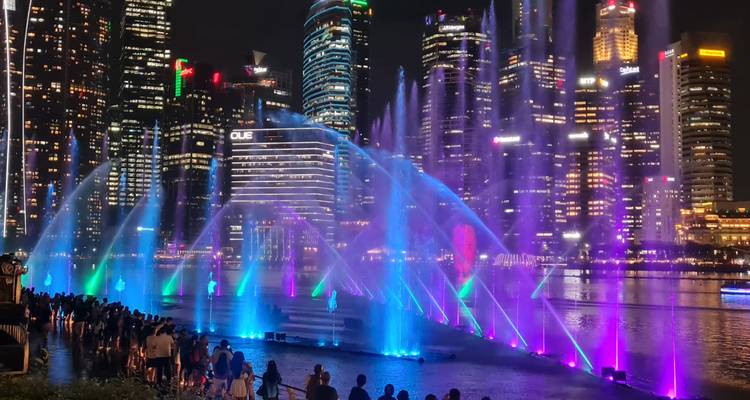 Vue nocturne des gratte-ciel de la ville avec un spectacle de lumières et de fontaines d'eau.