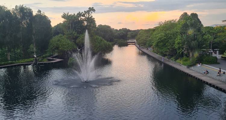 Beau parc avec une fontaine et des arbres au coucher du soleil.