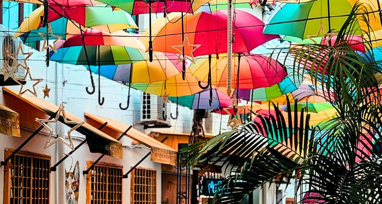 Rue avec des parapluies colorés et des décorations au-dessus.