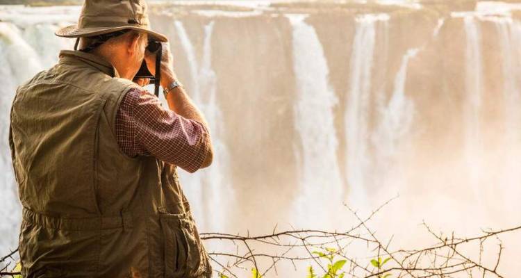 Homme prenant des photographies de chutes d'eau gigantesques.