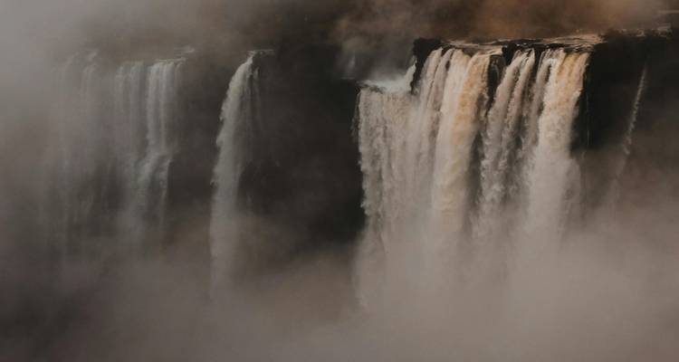 Vue brumeuse de hautes cascades avec une atmosphère embrumée.