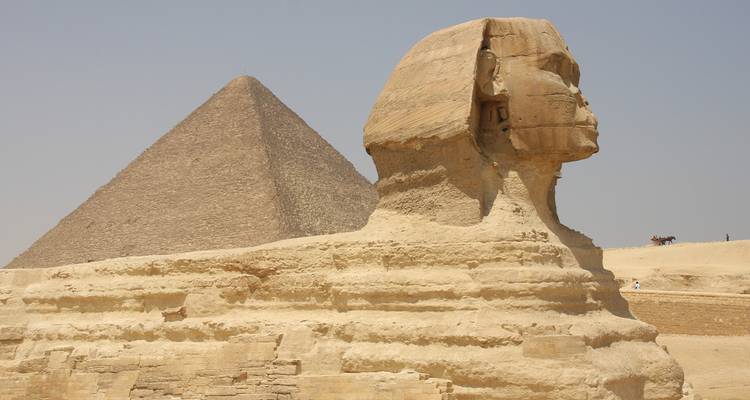 Grand Sphinx de profil avec la pyramide s'élevant derrière sous un ciel désertique brumeux