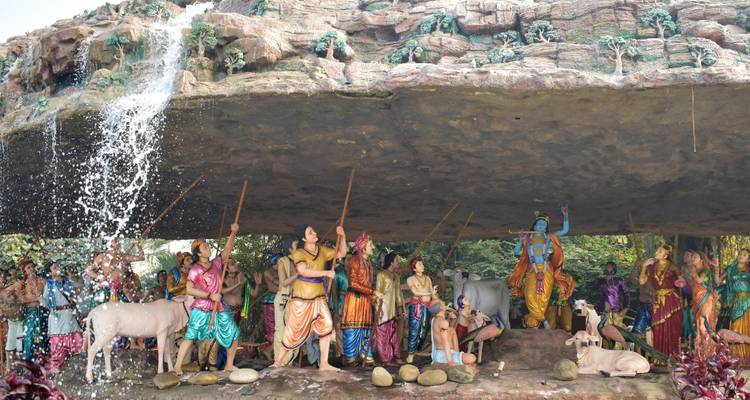 Des statues colorées représentant une scène mythologique sous un rebord rocheux.