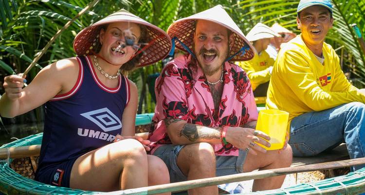 Des gens avec des chapeaux souriant lors d'une promenade en bateau dans un environnement luxuriant.