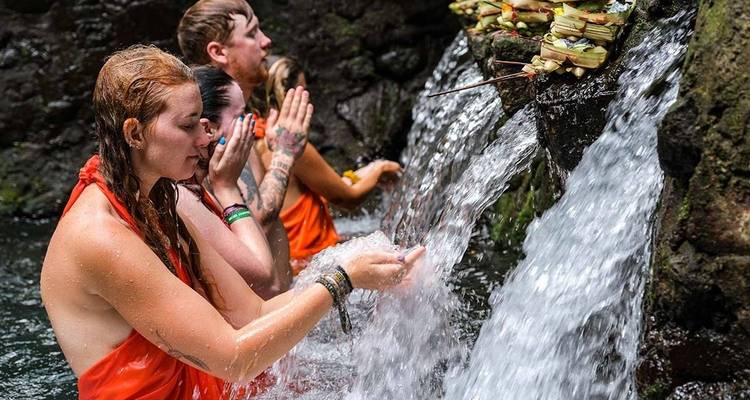 Des personnes effectuant un rituel aquatique près d'une petite cascade.