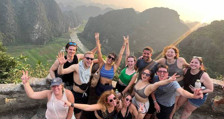 Groupe posant avec un paysage de montagne pittoresque au coucher du soleil.