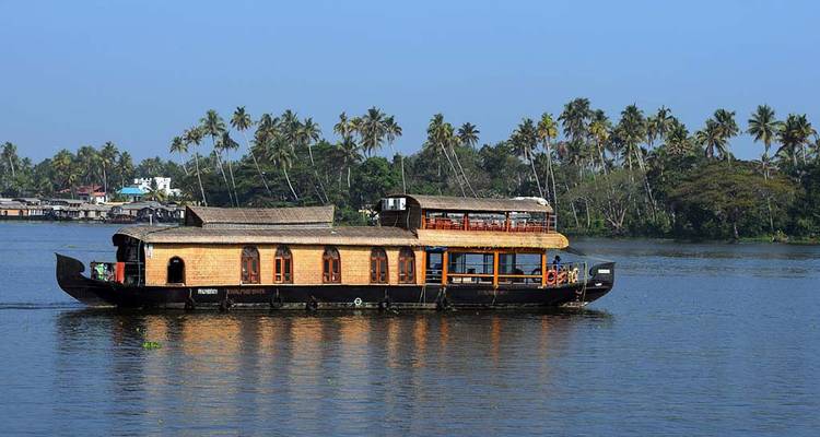 Houseboat on a backwater surrounded by palm trees.