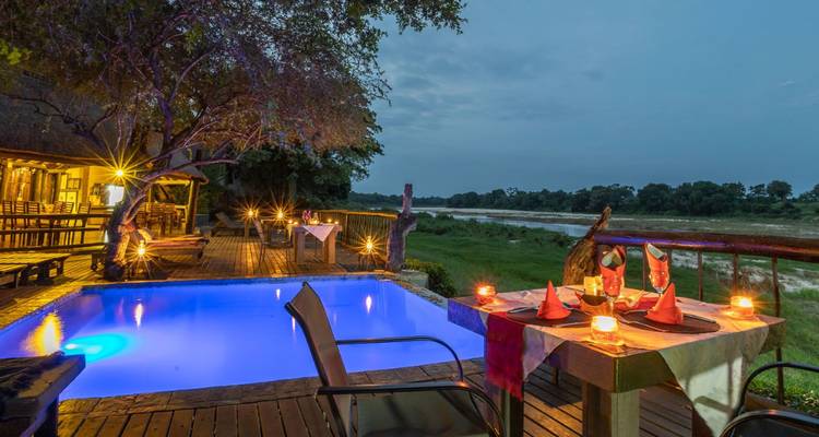 Comedor al aire libre junto a una pequeña piscina con vista al río.