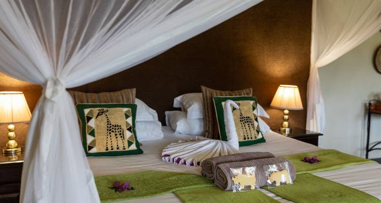 Habitación de hotel con cama con dosel decorada con motivos de animales.