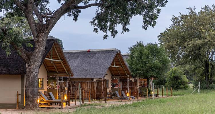 Edificios de alojamiento con área de asientos al aire libre rodeada de césped y árboles.