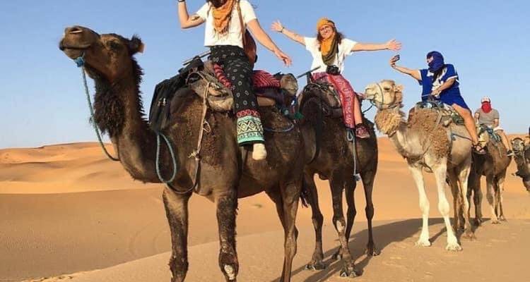 Des gens chevauchant des chameaux dans un désert, profitant d'une journée ensoleillée.