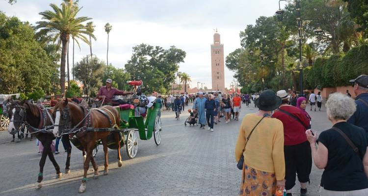 Scène de rue avec calèche tirée par des chevaux et des gens, avec une haute tour en arrière-plan.