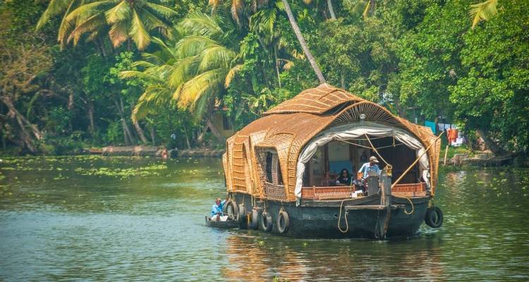 Péniche flottant sur les eaux verdoyantes luxuriantes du Kerala.