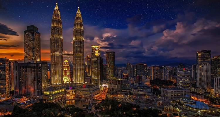 Paysage urbain de Kuala Lumpur la nuit avec des tours illuminées.