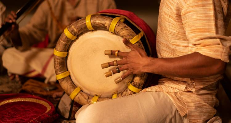 Persoon die een traditionele trommel bespeelt met gedetailleerde handgrepen.