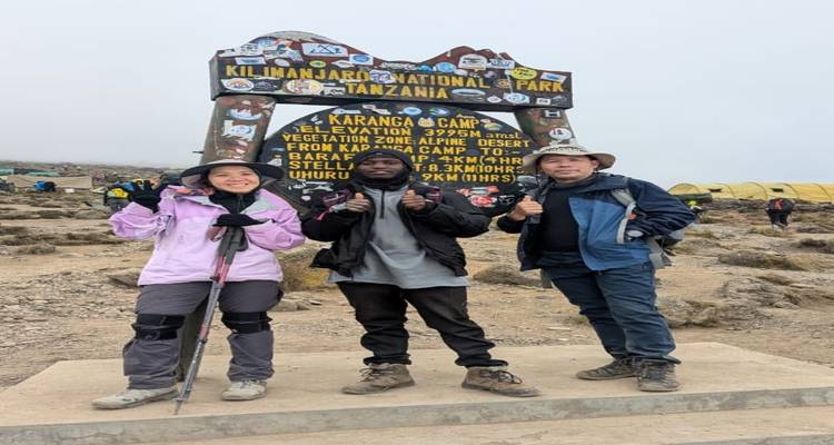 Groupe de randonneurs posant au camp de Karanga avec des tentes en arrière-plan.
