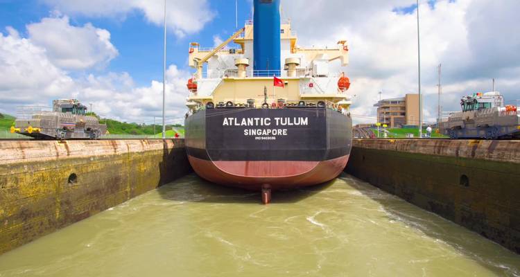 Ein großes Schiff, das mit Schleppern durch ein Schleusensystem navigiert.