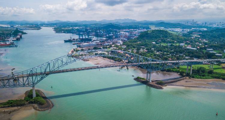 Brücke über einen Fluss in einer weiten Landschaft mit einer Stadt im Hintergrund.