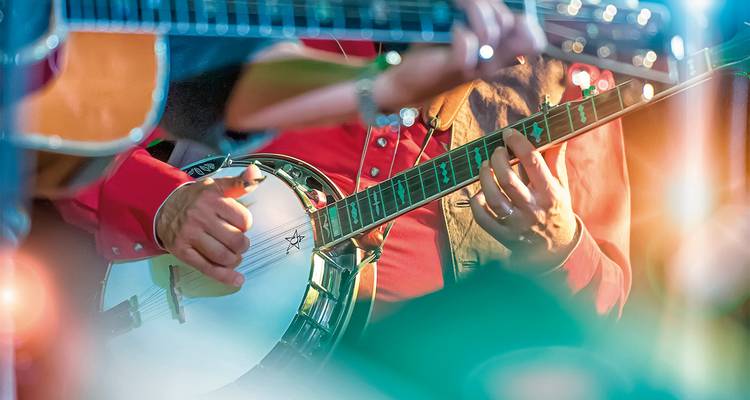 Gros plan d'un musicien jouant d'un instrument à cordes avec un bokeh coloré.