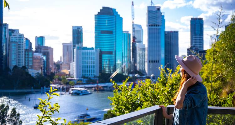 Personne observant une vue urbaine de gratte-ciel au bord d'une rivière.