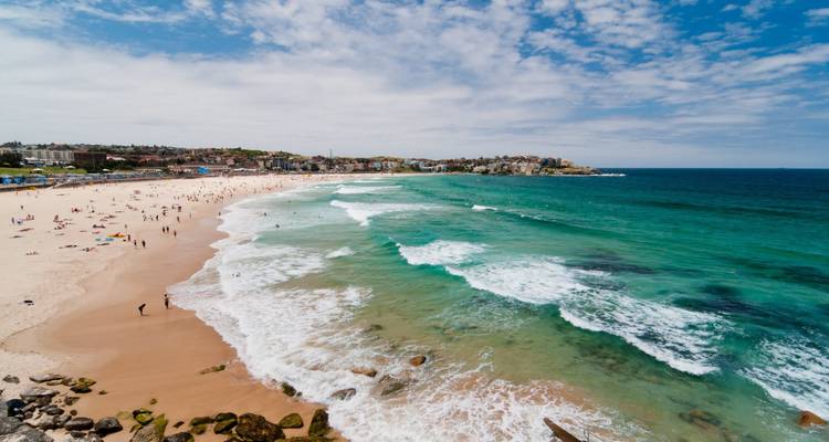 Plage populaire avec des eaux turquoise et des gens qui nagent.