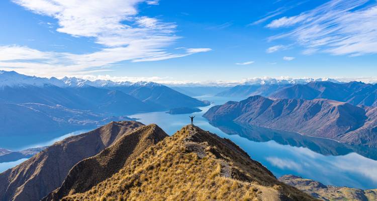 Personne debout sur une crête de montagne surplombant un lac.
