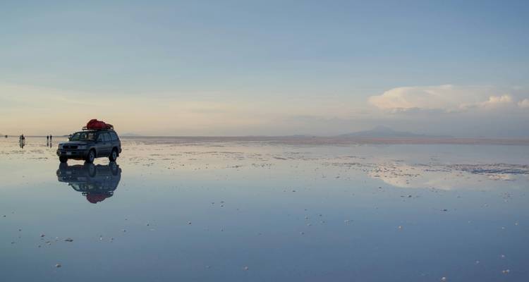 Jeep and people on reflective salt flat.