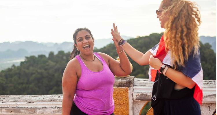 Deux femmes se tapant dans la main avec des vues panoramiques derrière elles.