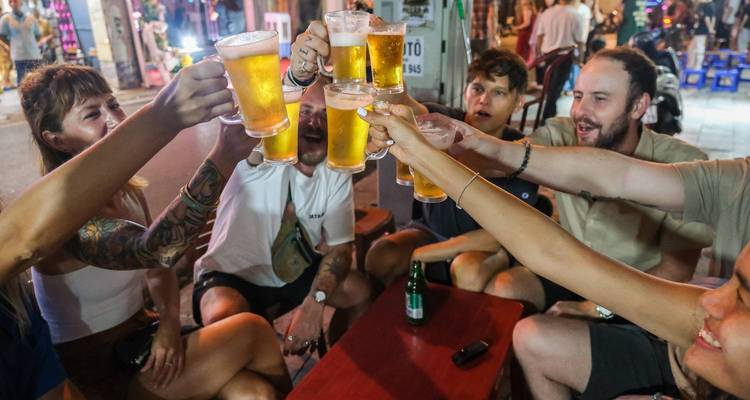 Groupe qui applaudit avec des boissons dans un cadre extérieur.