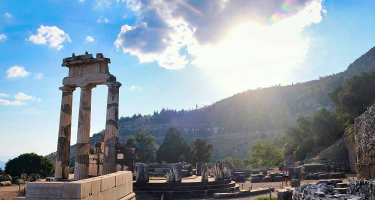 Ruines anciennes avec des colonnes contre un soleil couchant.