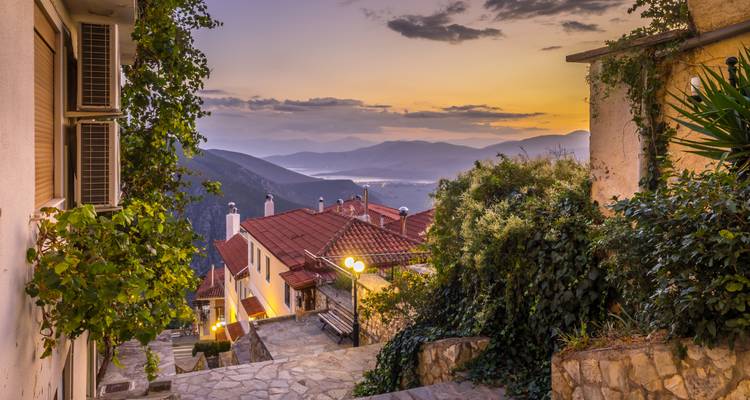 Village de montagne pittoresque avec vue sur un lac lointain au coucher du soleil.