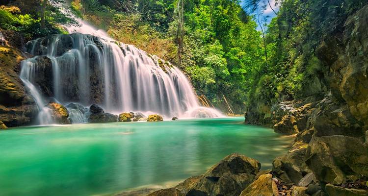 Espectacular cascada de la selva cayendo en una piscina turquesa rodeada de selva verde exuberante.