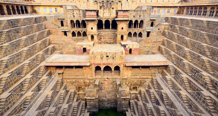 Enorme stepwell Chand Baori con patrones de escaleras simétricas descendiendo hacia agua verde