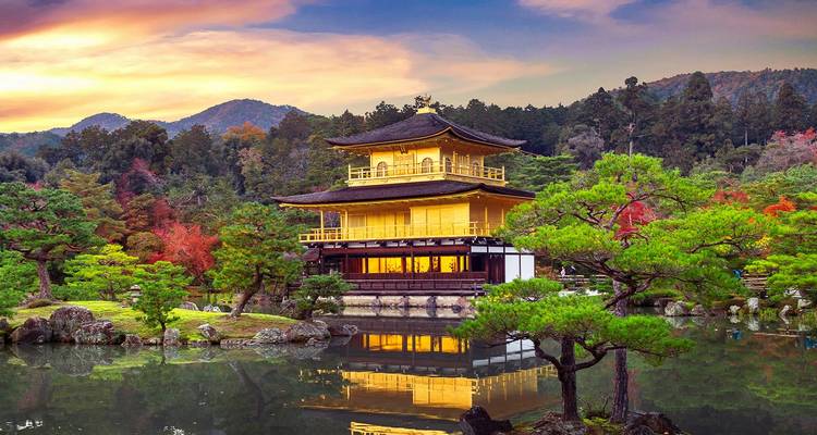 Golden Kinkaku-ji pavilion shining at sunset and perfectly reflected in a tranquil pond.