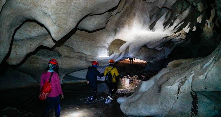 Des personnes explorant une grotte avec des lampes frontales et des lampes de poche.