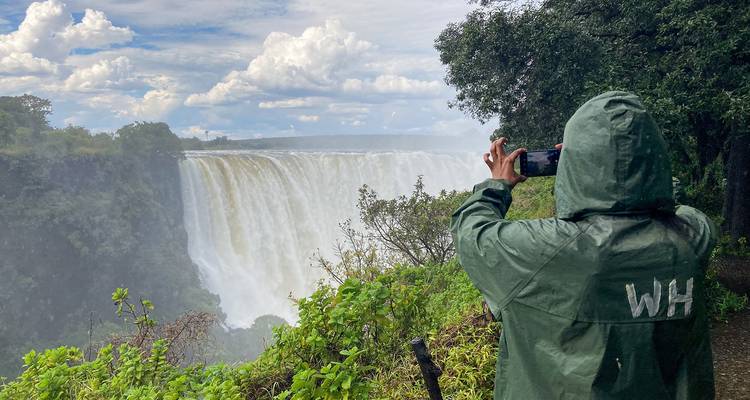 Person taking a photo of a large waterfall.