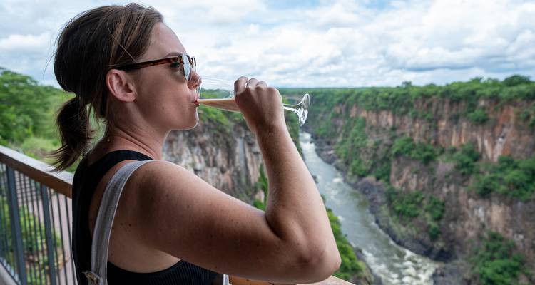 Woman enjoying a drink overlooking a canyon.