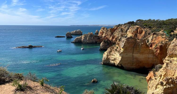 Kustrotsen met helder water en kleine bootjes in de Algarve.