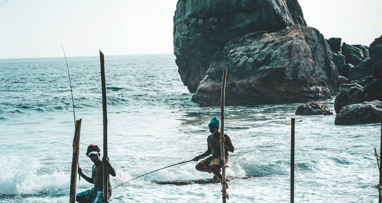 Pescadores tradicionales en zancos en el océano.