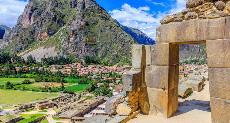 Ancient Incan ruins with a town and mountains in the background.