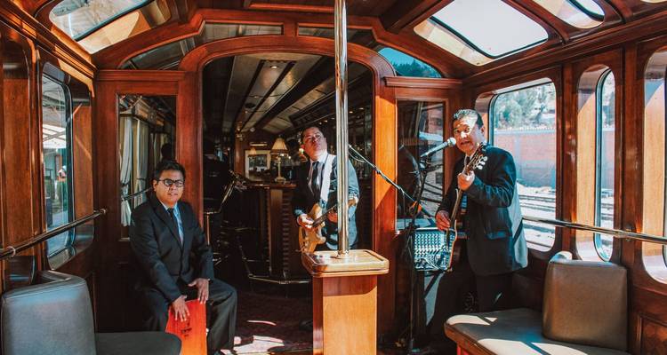 Musicians performing inside a wooden train carriage.