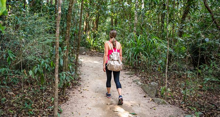 A woman walking on a forest path with a hiking backpack.