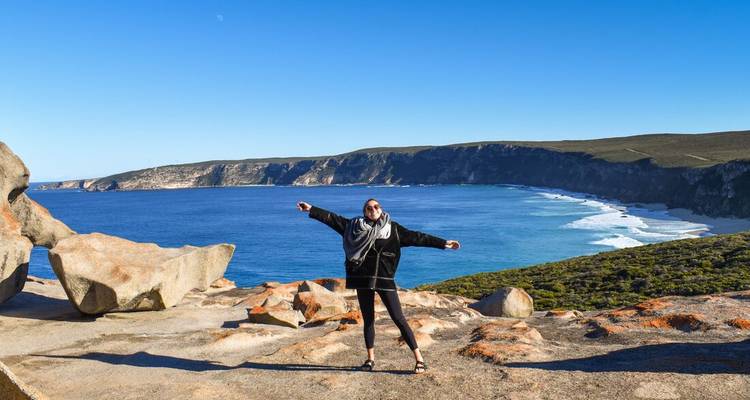 Personne posant sur une côte rocheuse avec vue sur l'océan.